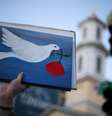 Manifestante segura uma placa com uma pomba da paz próximo à Casa Branca, nos EUA, após anúncio de cessar-fogo  Foto: Alex Wong/Getty Images