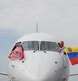 Pilotos do voo 3599 da American Airlines, partindo do Aeroporto Internacional de Miami com destino a Caracas, Venezuela, acenam com bandeiras venezuelanas e americanas antes da decolagem em um voo direto para a Venezuela, o primeiro entre os EUA e a Venezuela em sete anos, no Aeroporto Internacional de Miami, em Miami, Flórida, em 30 de abril de 2026.  Foto: AFP - CHANDAN KHANNA / RFI