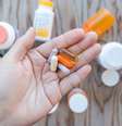 Uma mão segurando um monte de suplementos em uma palma aberta. Há frascos de suplementos como pano de fundo. Foto: Getty Images / BBC News Brasil