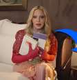 Madonna em sua cama e, na mesa, o frasco do óleo usado contra dores pelo corpo  Foto: Reprodução/YouTube
