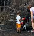 Uma mãe e seu filho inspecionam os arredores de sua casa em Le Porge, na segunda-feira, após ela ter sido destruída por um incêndio florestal  Foto: Reuters / BBC News Brasil
