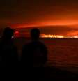Turistas observam incêndio florestal atingir uma área de mata próxima à baía de Arcachon, no oeste da França, em meio ao agravamento da seca após uma onda de calor e à escassez de água em grande parte do país, em 24 de julho de 2026.  Foto: REUTERS - Stephane Mahe / RFI