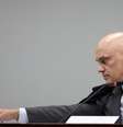 Alexandre de Moraes estende o braço para pegar algo durante julgamento  Foto: Reuters / BBC News Brasil