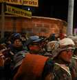 Pessoas que buscam por parentes desaparecidos e moradores da região aguardam enquanto militares formam um cordão de segurança após explosões que deixaram mortos e feridos no Regimento de Artilharia Mecanizada "Bolívar", em Viacha, Bolívia, em 4 de setembro de 2026.  Foto: REUTERS - Claudia Morales / RFI