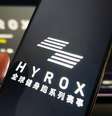 Mulher segura um telefone celular mostrando a marca Hyrox  Foto: Getty Images / BBC News Brasil