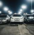Foto: Cena noturna em um estacionamento bem iluminado com vários carros estacionados e postes de luz. ( Pexels) / Gávea News