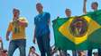Com bandeira do Brasil com imagem do pai, Flávio diz que Bolsonaro lhe entregará faixa presidencial