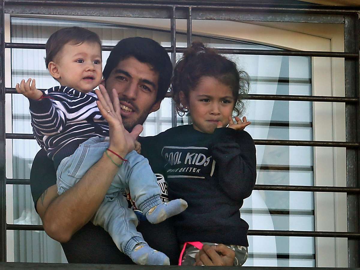 Suárez atende fãs com os filhos no colo no Uruguai