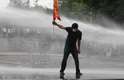 16 de junho - Manifestante segura bandeira enquanto policiais usam jatos de água para dispersar manifestação em Ancara