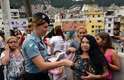 25 de junho - Policial distribui panfletos a manifestantes na favela da Rocinha, no Rio