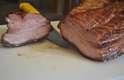 O corte na carne revela as camadas de gordura e carne curada e defumada que formam o bacon caseiro.