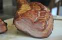 O corte na carne revela as camadas de gordura e carne curada e defumada que formam o bacon artesanal produzido na laje do restaurante de SP.