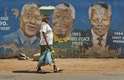 7 de dezembro - Mulher carrega verduras em frente a muro com pintura de Nelson Mandela