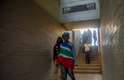Enrolada na bandeira sul-africana, mulher anda pelos corredores do estádio