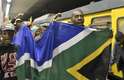10 de dezembro - Sul-africanos descem do trem com a bandeira do país e se dirigem ao local da cerimônia