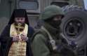 1 de março de 2014 - Religioso ortodoxo reza próximo aos militares uniformizados em cidade da Crimeia. O senado da Rússia autorizou a invasão de tropas russas à Ucrânia neste sábado, 1 de março