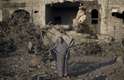 8 de julho - Uma mulher palestina é vista no meio de destruição, após um ataque militar israelense na cidade de Gaza