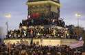 Pessoas escalam o monumento da Queda da Bastilha durante os últimos momentos da marcha pela liberdade