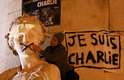 Homem toca estátua pichada ao lado do símbolo da marcha, "Je Suis Charlie"