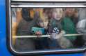 Dia 25/2 - Crianças olham Kiev da janela de um trem de evacuação durante a guerra