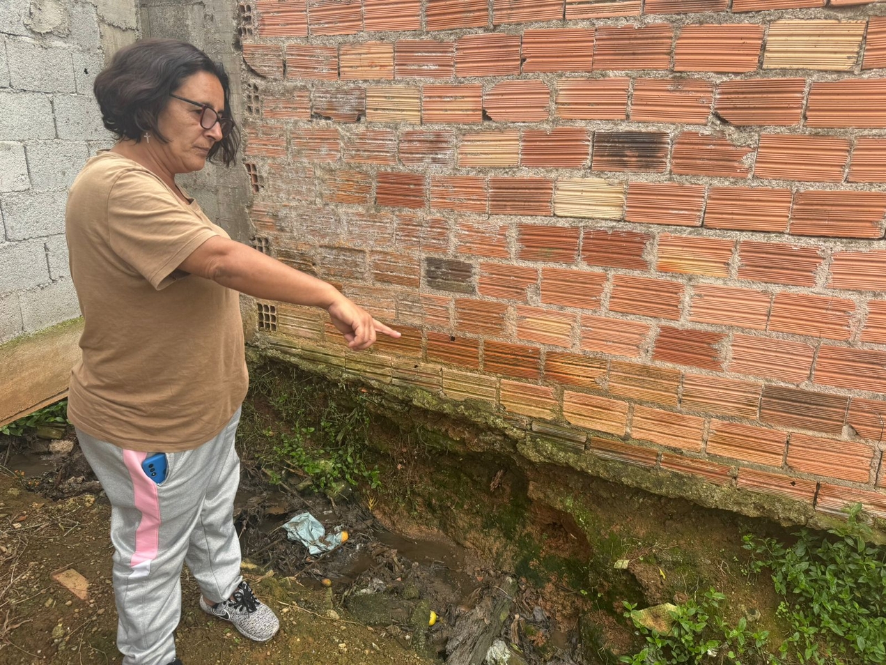 Luciane mostra esgoto a céu aberto que passa na lateral de sua casa, bem onde fica sua cozinha