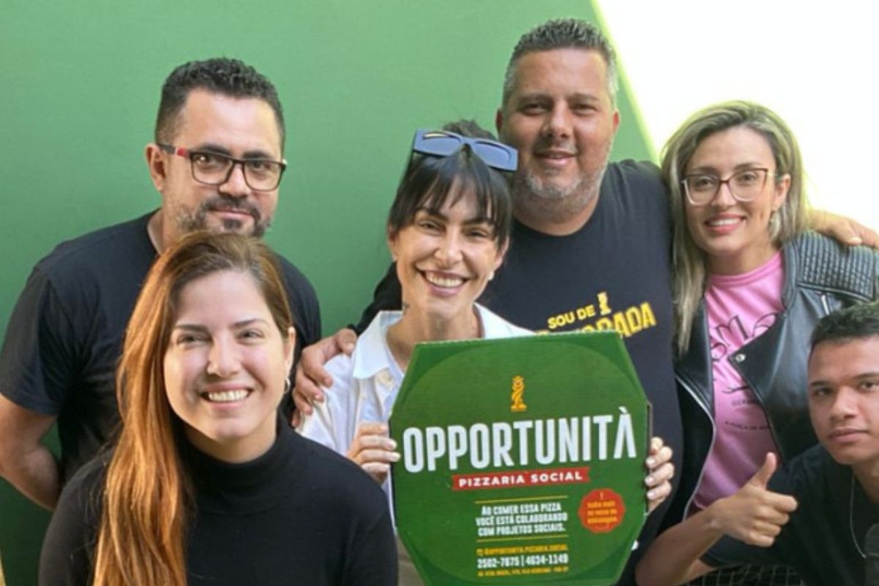Ao centro, Leo Precioso e Cleo Pires posam juntos; atriz segura caixa da pizzaria social