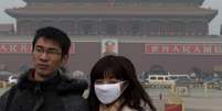 Mulher utiliza m&aacute;scara enquanto visita Pra&ccedil;a de Tian'anmen em Pequim: polui&ccedil;&atilde;o atingiu n&iacute;veis perigosos e encobriu pr&eacute;dios na China  Foto: AP