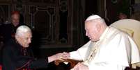 <p>Em 2005, o então cardeal Ratzinger foi fotografado cumprimentando o papa João Paulo II, que morreria no mesmo ano</p>  Foto: Osservatore Romano / EFE
