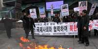 Ativistas queimam bandeira da Coreia do Norte durante um protesto em Seul, na Coreia do Sul  Foto: AFP