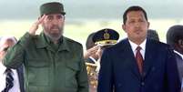 Presidente cubano Fidel Castro faz saudação durante a execução do hino nacional em sua primeira visita à Venezuela durante o governo Chávez, em 26 de outubro de 2000  Foto: AFP