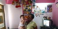 Marisol Aponte, 49 anos, posa para foto com o filho em sua casa  Foto: BBC News Brasil