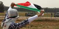 Manifestante exibe bandeira palestina durante protesto no sul da Faixa de Gaza  Foto: Reuters