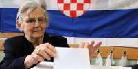 Mulher deposita voto em urna de seção eleitoral em Zagreb, capital do país  Foto: AFP