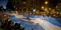 Manifestantes carregam uma enorme bandeira argentina com uma faixa negra em sinal de luto  Foto: AP