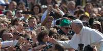 Papa interage com criança ao chegar para a audiência geral na Praça São Pedro   Foto: AP