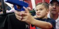 Heath Bryant ajuda seu filho Tate, 5 anos, a disparar usando arma similar a de videogames durante dia da juventude na conven&ccedil;&atilde;o da NRA, em Houston, em 5 de maio  Foto: AP