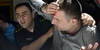 Policial auxilia homem ferido na manifestação  Foto: Reuters