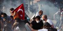 <p>Manifestantes se protegem de bombas de gás lacrimogêneo jogadas pela polícia em Ancara</p>  Foto: AP
