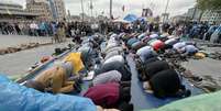 Manifestantes dão as mãos para proteger outros que rezam na Praça Taksim, em Istambul, nesta sexta-feira  Foto: AP