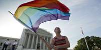 Ativista Vin Testa agita bandeira do movimento gay na frente do prédio da Suprema Corte americana, em Washington  Foto: AP