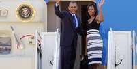 Obama e Michelle abanam antes de entrar no Air Force One, na base aérea Andrews  Foto: AP