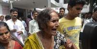 Mulher chora após receber a confirmação de que seu neto morreu após ingerir a refeição contaminada  Foto: Reuters