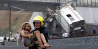 Bombeiro retira uma criança ferida do local do acidente  Foto: AFP