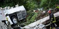 <p>Bombeiro trabalha junto aos destroços de ônibus que saiu de rodovia nas proximidades de Avellino</p>  Foto: AP