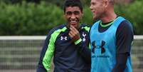 <p>Paulinho ri ao lado do veterano goleiro Brad Friedel durante seu primeiro treino no Tottenham</p>  Foto: Divulgação