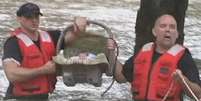 Socorristas carregam o bebê resgatado durante a enchente   Foto: BBC News Brasil
