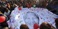 <p>Pessoas abrem um cartaz com a imagem de Nelson Mandela durante as comemora&ccedil;&otilde;es pelo seu 95&ordm; anivers&aacute;rio, em frente &agrave; cl&iacute;nica onde o ex-presidente da &Aacute;frica do Sul est&aacute; internado, em Pret&oacute;ria</p>  Foto: Siphiwe Sibeko / Reuters