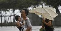 Moradores de Hong Kong tentam se proteger do vento forte  Foto: AP