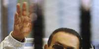 <p>Ex-presidente egípcio Hosni Mubarak acena para seus apoiadores de dentro de uma cela em uma corte de uma academia de polícia</p>  Foto: Stringer / Reuters