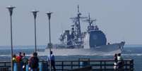 <p>Turistas observam o navio de guerra cruzador de mísseis USS Mahan partindo para o oceano Atlântico, perto de Virginia Beach, nos Estados Unidos, em setembro de 2003</p>  Foto: Chip East cme / Reuters